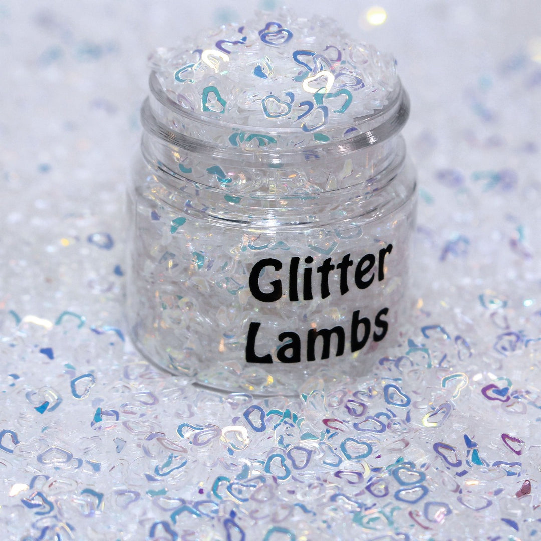Angel is a white iridescent hollow heart sequin plastic glitter by GlitterLambs.com. Great for snowglobe tumbler  cups, snowglobe pens, drip cups, shaker cards, shaker hairbows, body and hair glitter, 3d nail art but it's stiff and won't curve to a nail, resin, resin shakers, etc.