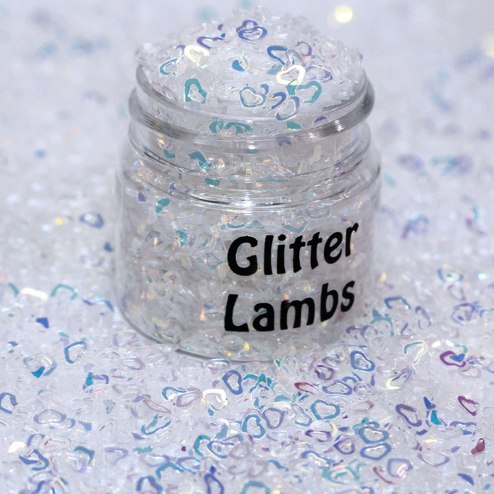 Angel is a white iridescent hollow heart sequin plastic glitter by GlitterLambs.com. Great for snowglobe tumbler  cups, snowglobe pens, drip cups, shaker cards, shaker hairbows, body and hair glitter, 3d nail art but it's stiff and won't curve to a nail, resin, resin shakers, etc.