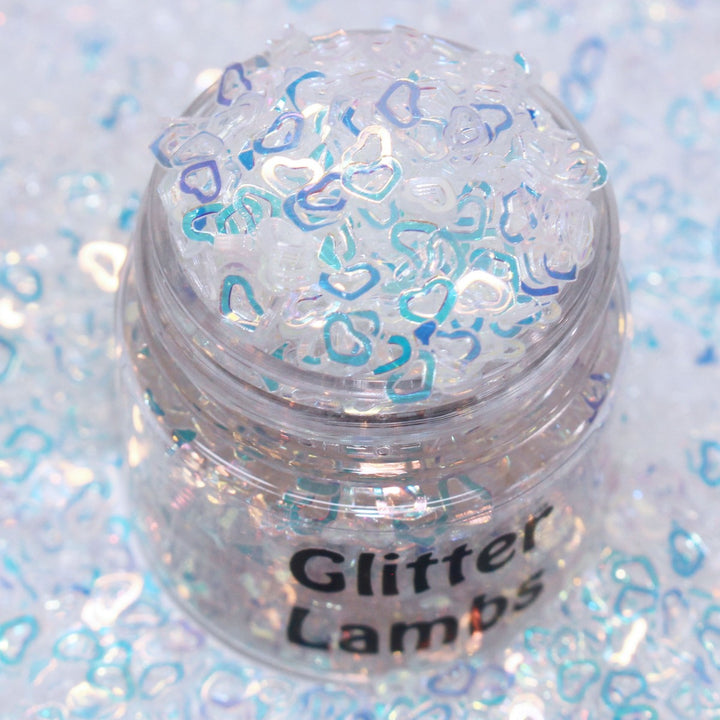 Angel is a white iridescent hollow heart sequin plastic glitter by GlitterLambs.com. Great for snowglobe tumbler cups, snowglobe pens, drip cups, shaker cards, shaker hairbows, body and hair glitter, 3d nail art but it's stiff and won't curve to a nail, resin, resin shakers, etc.